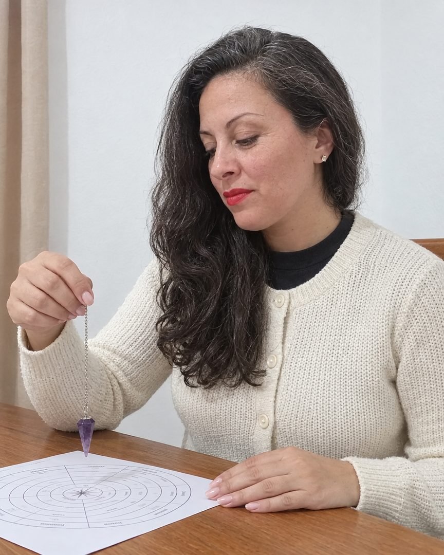 Mariana Medici mirando un péndulo de amatista sobre un tablero radiónico