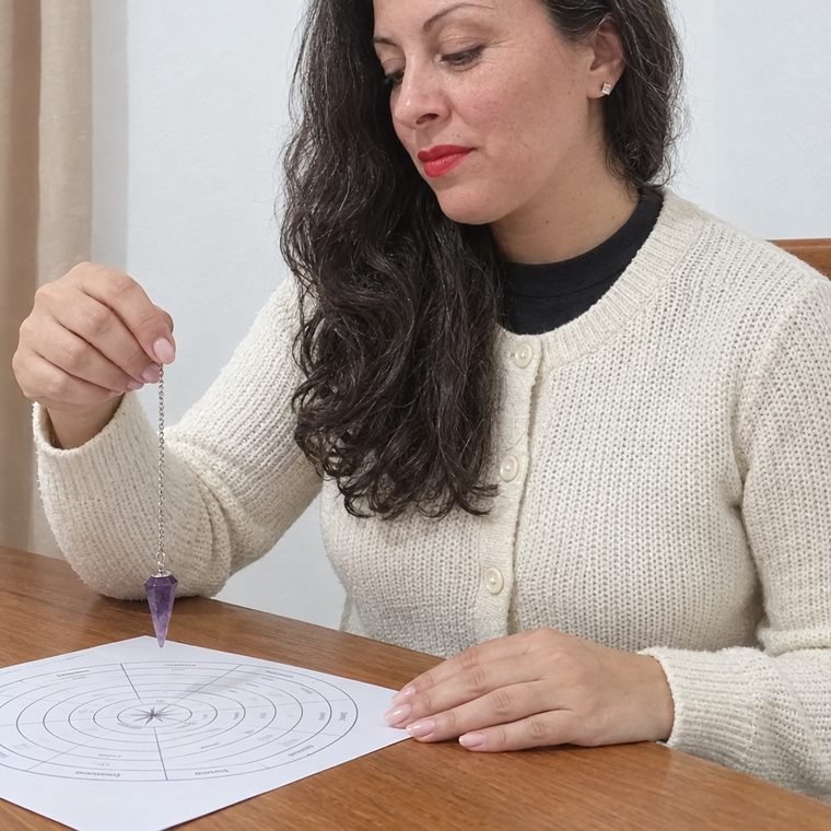 Mariana Medici mirando un péndulo de amatista sobre un tablero